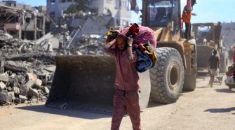 Un hombre con un hatillo con sus pertenencias pasa ante varias excavadoras